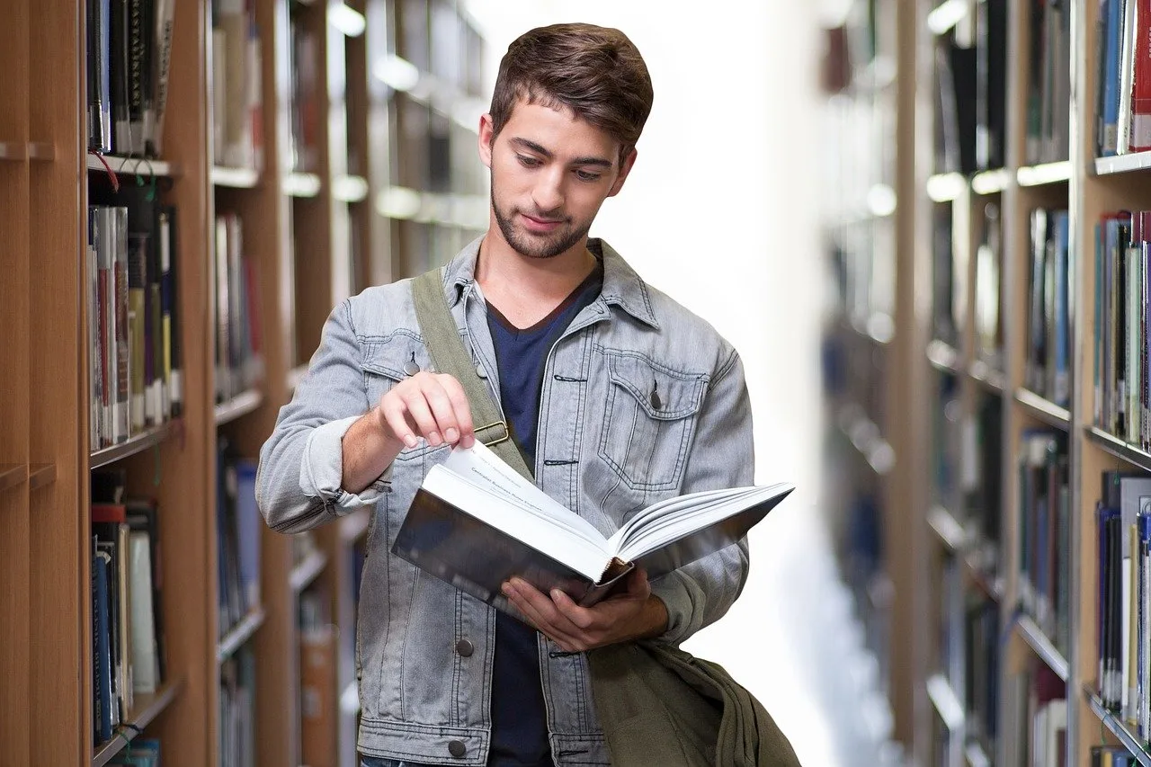 Étudiant en bibliothèque consultant un livre